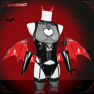 A black and red latex devil costume displayed on a white mannequin against a dark red background with bat silhouettes. The costume includes red devil horns, red bat wings, black thigh guards, and a white heart on the chest.