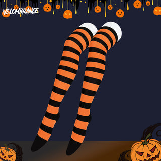 A pair of thigh-high striped stockings with bold orange and black horizontal stripes, shown on a stylized illustrated leg form against a dark navy background with Halloween decorations including pumpkins and a Velombrance logo.