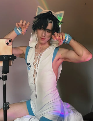 A person posing in a white and blue cat-themed costume with a lace-up front, matching shorts, and cat ears headband, photographed indoors with a phone on a tripod and colored lighting.
